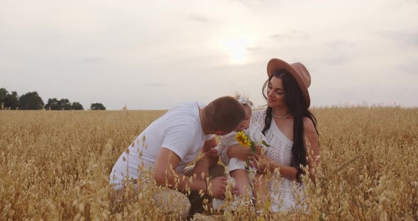 Young Parents With A Child Are Walking In A Wheat Field