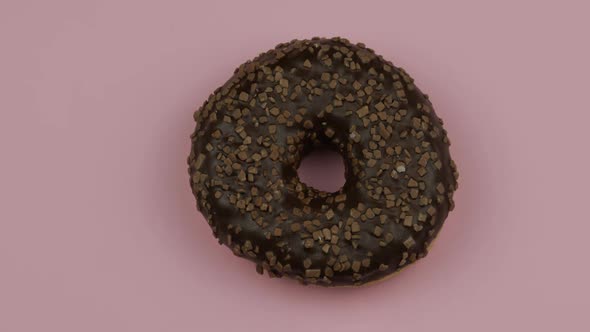 Sweet Donut Rotating on Pink Background. Top View. Tasty, Fresh Sprinkled Donut alt