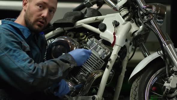 guy mechanic in blue overalls next to a motorcycle