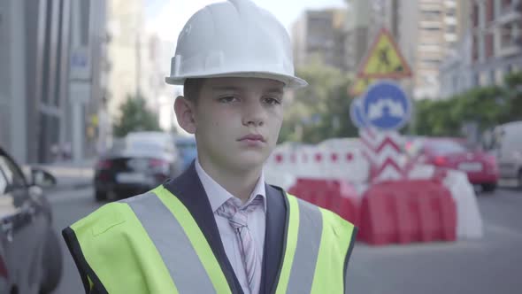 Portrait Cute Little Boy Wearing Business Suit and Safety Equipment and Constructor Helmet Standing alt
