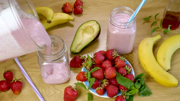 Strawberry Banana Smoothie is Poured Into a Glass on the Background of Fresh Fruits alt