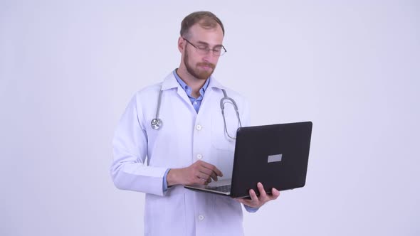 Happy Bearded Man Doctor Thinking While Using Laptop