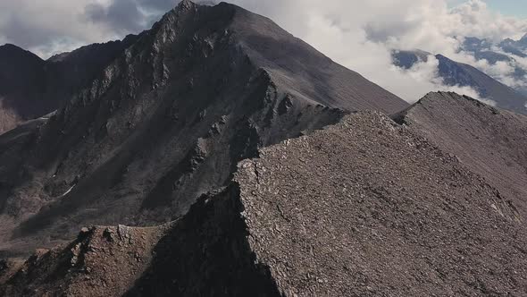 Steep Rocky Mountain Rock Peak Slopes and Clouds in a Valley