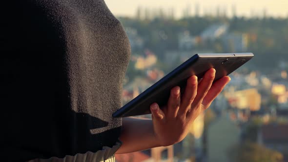 Young Black Woman Works on Tablet - Buildings in the Background - Closeup alt