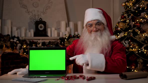 Smiling Santa Claus Points Finger at Laptop Green Screen Christmas Shopping alt