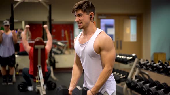 Side shot of young bodybuilder doing dumbbell shoulder fly or lateral raises, which works the deltoi alt