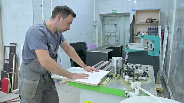 A man works on a machine that processes wooden workpieces in an assembly alt