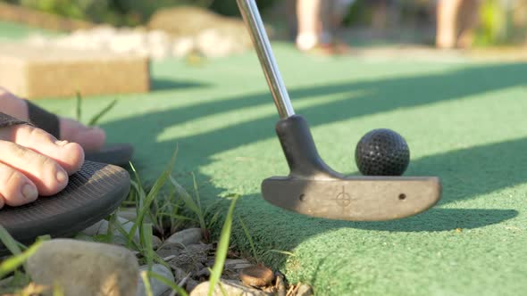 A Man in Sandals Putting on a Mini Golf Course, Close Up Slow Motion alt