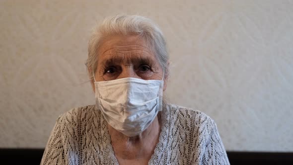 Close-up Portrait of a Happy Elderly Gray-haired Woman in a Protective Medical Mask
