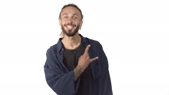 Cheerful Bearded Man with Tattoos on Body and Face Smiling Joyful Showing Rocknroll Gesture Standing alt