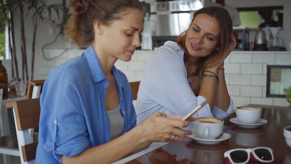 Lesbian Couple Chatting in Cafe. Two Beautiful Women Gossiping and Drinking Coffee alt