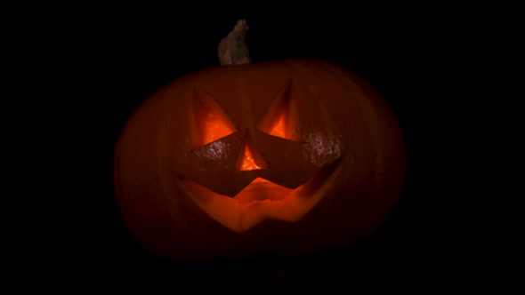 Funny and Scary Halloween Pumpkin with a Candle Inside Isolated on Black Background
