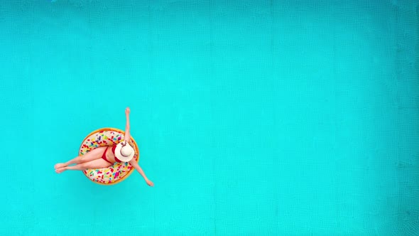 Aerial View of a Woman in Red Bikini Lying on a Donut in the Pool alt