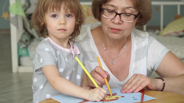 Elderly Woman with Little Girl Paint Goldfish on Paper with Colored Pencils