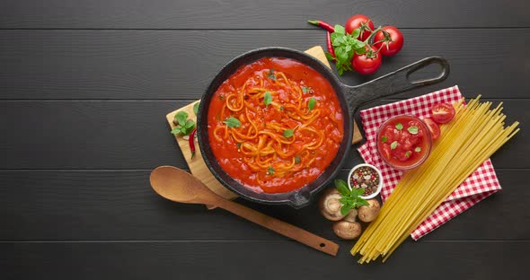 Cooking homemade spaghetti with tomato sauce in cast iron pan 