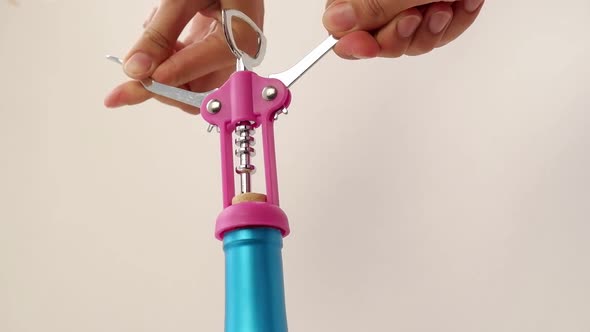 A Womans Hand with an Opener Opens a Wooden Cork From a Bottle of Wine Alcoholic Drink on a Beige alt