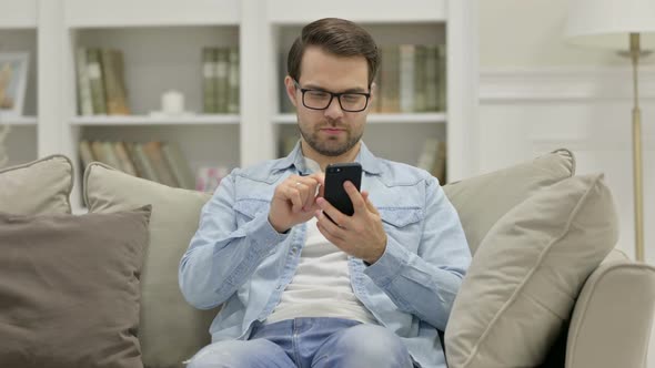 Young Man Using Smartphone at Home alt