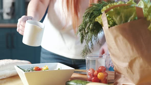 woman prepares a vegetable salad pours the sauce mix alt