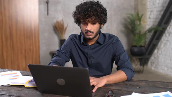 Executive Indian Male Office Employee Doing Paperwork While Sitting at the Desk