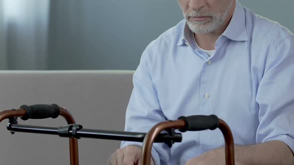 Old Man Sitting and Looking at Walking Frame, Spine Trauma, Indecisiveness alt