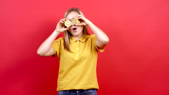 Happy, Optimistic Girl in a Yellow T-shirt, Covering Her Eyes with Lemon alt