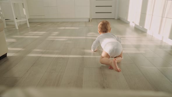 Cute Happy Little Toddler Baby Boy is Crawling on a Wooden Floor at Home alt
