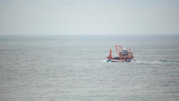 A vessel slowly sailing across the horizon on a calm turquoise ocean alt