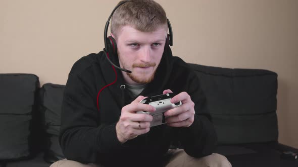 Young Caucasian Man in Black Hoodie Playing Video Games with a Gamepad