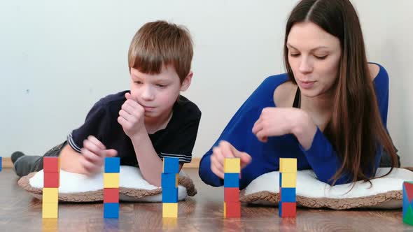 Building a Small and Big Towers From Blocks and Cubes. Mom and Son Playing Together