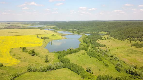 A drone aerial shot of a lake and forest hill in the countryside