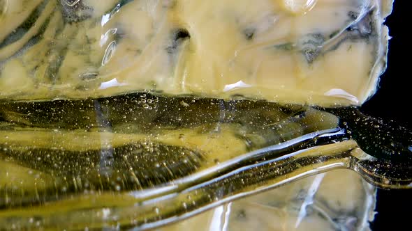 Drops of honey flowing down from the Dorblu cheese on a mirrored black background. alt