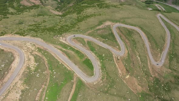 Top view of the mountain road through the green field