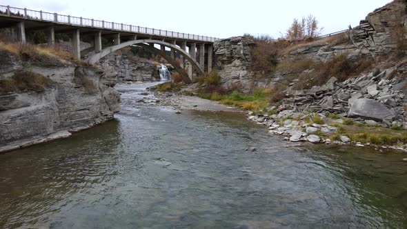 Slow motion aerial shot approaching an old arch bridge near Lundbreck falls in southern Alberta, Can alt