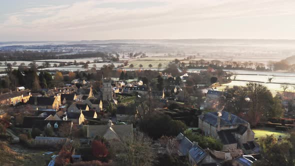 Aerial drone video of a Cotswolds Village, English countryside fields and scenery with houses, prope alt
