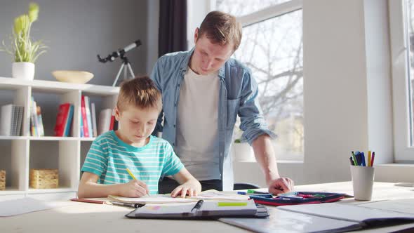 Boy and Father Doing Homework at the Table. Child is Learning at Home. alt