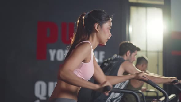 Shot of active sport people sitting on stationary bicycles or exercise bikes machine in gym stadium. alt