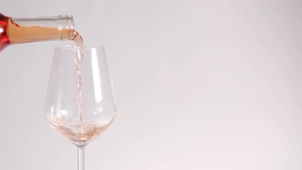 Slow-motion pouring rose wine on white background