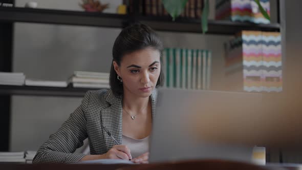 Woman Working From Home Using Laptop Computer While Reading Text Message alt