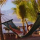 Young Woman Wearing a Sitting in the Sun and Swinging in a Hammock While Looking Out at the Ocean - VideoHive Item for Sale