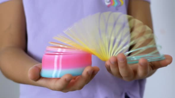 Kid holds a Slinky toy in his hands. A rainbow spiral for games popular in the '90s. alt