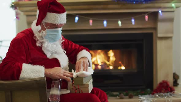 Santa Claus wearing face mask sanitizing the gift box at home alt