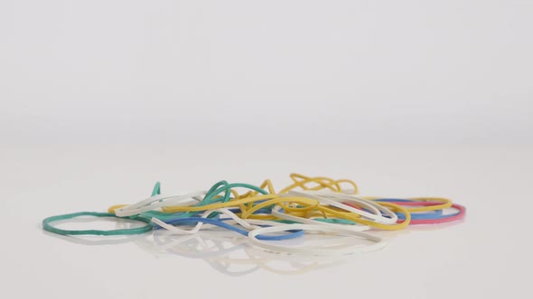 Ring shaped rubber bands on white slow tilt 4K footage alt