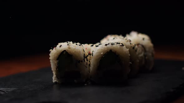 Portion of White and Black Sesame Sprinkled Rolls with Cucumber and Salmon in a Changing Light on a alt