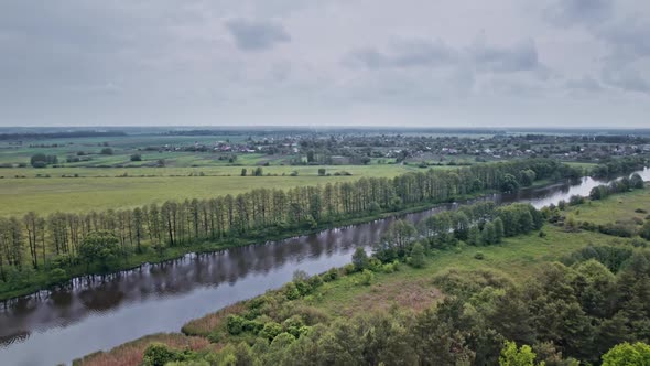 Top View of the River Surrounded By Trees and Meadows alt