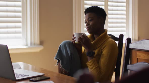 African american woman drinking coffee while working from home alt