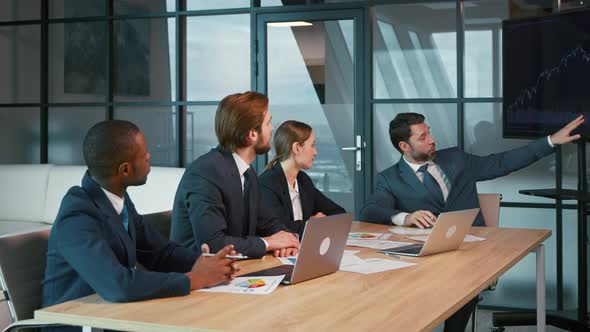 Corporate manager showing development graph using tv technology alt