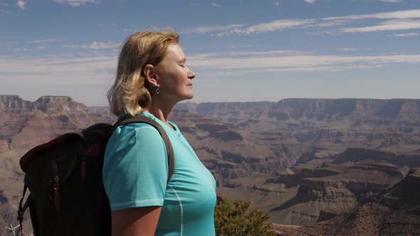 Female Tourist Stands At The Top Of Grand Canyon Inhaling Clean Fresh Air alt