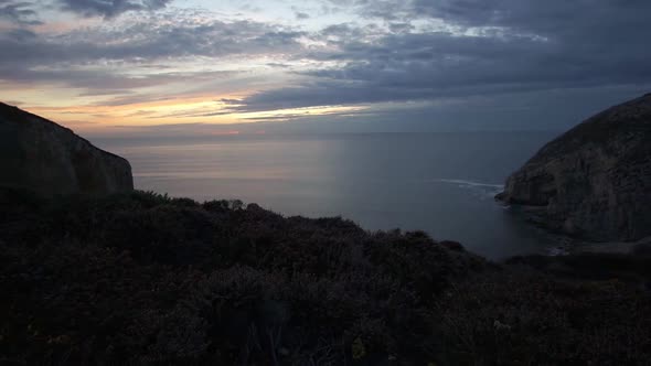 Timelapse of sunset at rocky coastline of Cap de la Chevre with dramatic clouds on the sky, France alt