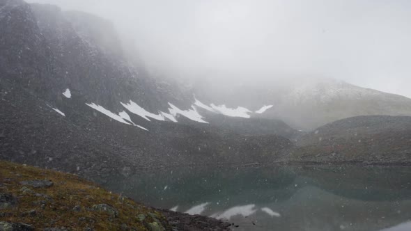 Large Flakes of Snow Fly Over the Ridge and Lake