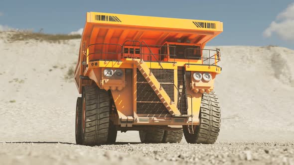 Yellow big dump truck standing in the middle of a vast dig site quarry. 4KHD alt